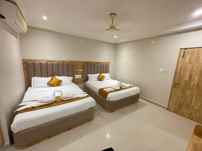 Authentic photograph of Deluxe Room at Yadava Satram Srisailam showing air conditioning, television, and neatly arranged beds